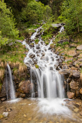 Fototapeta na wymiar A small cascade waterfall, near a village of Encamp, Andorra. Located in the Pyrenees mountain