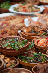 A Chinese Dinner with various plates stapled above each other with vegetable and meat, arranged in traditional clay pots