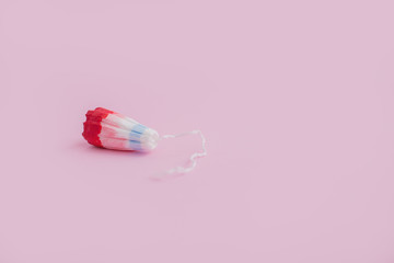 Female swab with a drop of red blood on a pink background