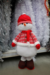 toy snowman in a red cap and a red scarf and a red jacket against a wall of decorative rain