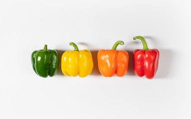 Colored bell peppers on white background. Green, yellow, orange and red pepper.