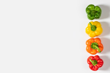 Colored bell peppers on white background. Green, yellow, orange and red pepper. Food concept.