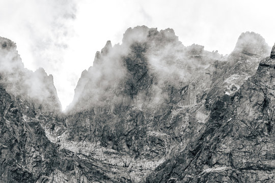 Detail of a mountain rock face, background or wallpaper picture of big wall rock climb, clouds and mist, stone and rock surface. Huge rock wall of granite in High Tatras, Slovakia.