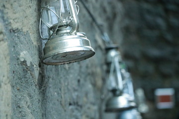 Die alte Petroleumlampe aus Metall hängt an der Steinmauer. Die Petroleumlampe leuchtet noch nicht.