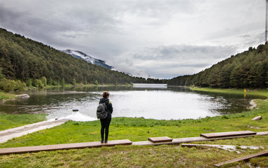 Fototapeta na wymiar A tourist girl standing next to Lake Engolasters, in the Encamp parish of Andorra, is a lake formed in a glacial depression. It is located close to Andorra La Vella, the capital of Andorra.