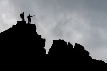 Two men standing on s rock and pointing to the distance. Mountain explorer collage. Double exposure...