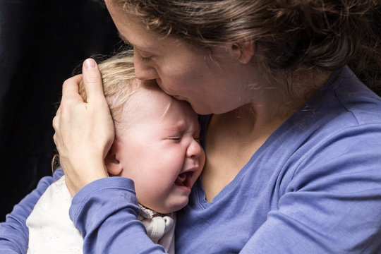 bébé pleure dans les bras de sa mère
