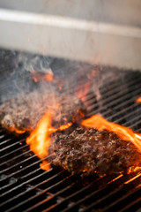 cooking burgers on hot grill with flames