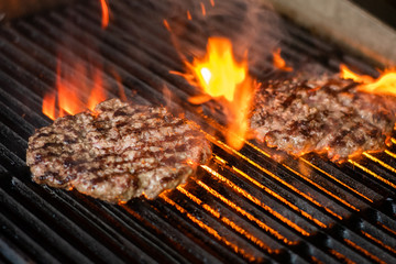cooking burgers on hot grill with flames - obrazy, fototapety, plakaty