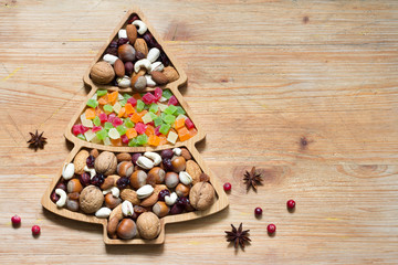 Christmas tree with nuts and dried fruits on wooden background