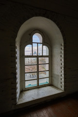 Fototapeta premium Domes of the old church are visible through the arched window of the old tower
