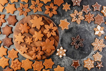 Various christmas gingerbread cookies on dark table with flour