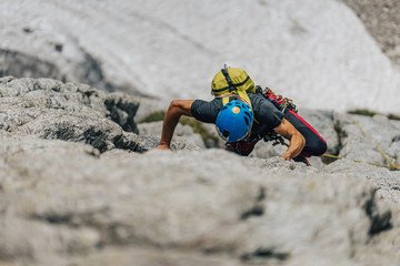 Obraz premium A climber or a mountaineer ascending a big rock face. Man, an alpinist, on extreme adventure sport climb in big rock wall. Climbing in High Tatras, Slovakia.
