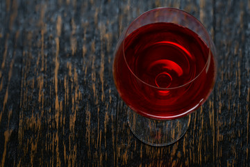Full glass of red wine on a black wooden background, top angle.