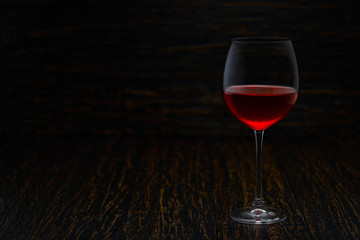 Full glass of red wine on a black wooden background, with copy space.
