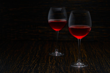 two glasses of red wine on a black wooden background, with copy space.