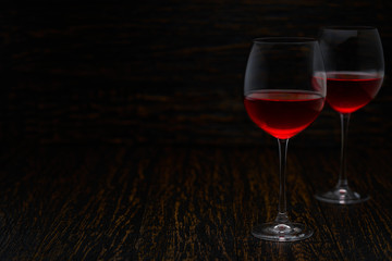 two glasses of red wine on a black wooden background, with copy space.