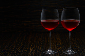 two glasses of red wine on a black wooden background, with copy space.