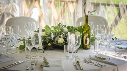 Decorated wedding tables with numbers on bottles and beautiful rose compositions on the tables