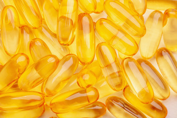 group of yellow fish oil capsules on a white table