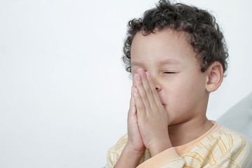 boy praying to God with hands held together on white background stock photo