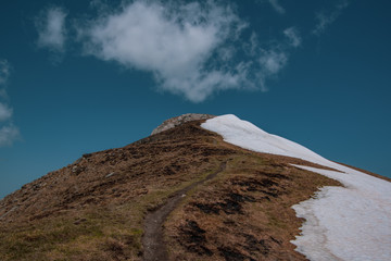 Landscape view of a snow-capped mountain. The path leading to the highest peak Golem Korab. SpringTime in Mavrovo national park, North Macedonia.
