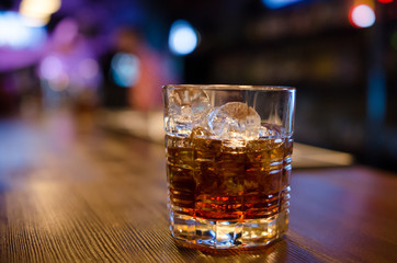 Glass of whiskey and ice on the background of the bar