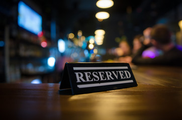 Restaurant reserved table sign standing on wooden table in bar