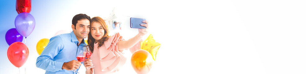 Young couple selfie on smartphone. Caucasian man with an Asian woman. Celebrating the New Year with smile happiness in the home. Panoramic web banner on white background with copy space concept.