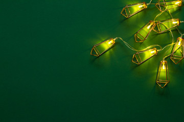 Christmas background or concept, luminous copper garland on a green background