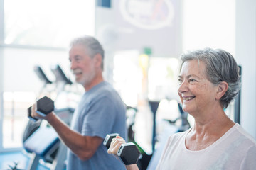 couple of two seniors training together at the gym with dumbbells in thei hand - heealthy and...