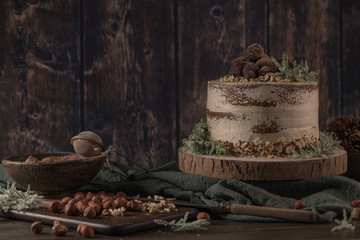 Delicious naked chocolate and hazelnuts cake on table rustic wood kitchen countertop.