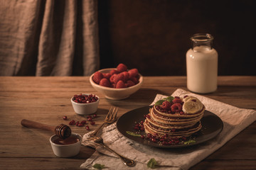 Pancakes with raspberries, banana slices, pomegranate seeds and honey