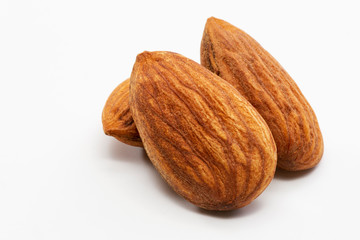 Close up shot of three roasted almonds on a white background.