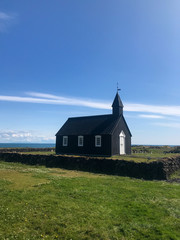 Fototapeta premium Lonely black church sitting in a grassy field