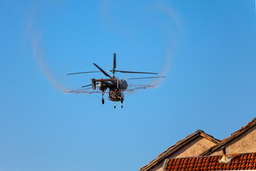 Fototapeta na wymiar Pest extermination helicopter spraying pesticide while flyng over residential buildings