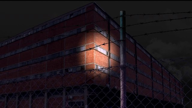 Spotlight moves across a brick building at night