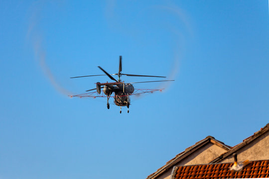 Pest extermination helicopter spraying pesticide while flyng over residential buildings
