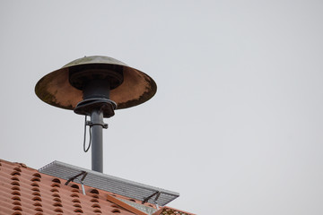 fire siren on a roof to alarm the fire fighter brigade in case of an emergency, gray sky with copy space - obrazy, fototapety, plakaty