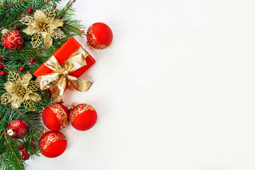 Bożonarodzeniowe tło - gałęzie świerku, prezenty i czerwone i złote ozdoby na białym tle