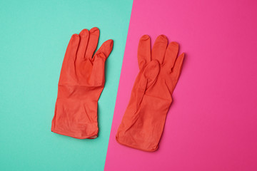 pair of rubber orange gloves for cleaning the house on a colored background