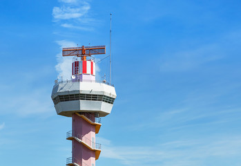Radar  air traffic control tower in international airport while airplane taking off under blue sky.       