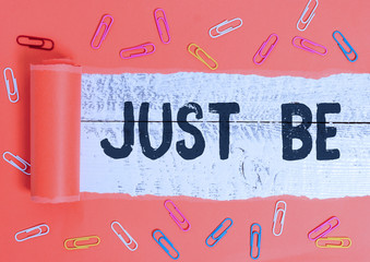 Text sign showing Just Be. Business photo text to do the things you believe in and want to be accepted for Paper clip and torn cardboard placed above a wooden classic table backdrop