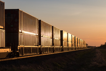 Obraz premium Train Carrying Shipping Containers in Golden Sunset on the Canadian Prairie