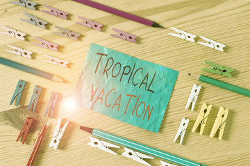 Conceptual hand writing showing Tropical Vacation. Concept meaning taking a holiday in countries either side of the equator Colored crumpled papers wooden floor background clothespin