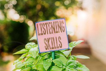 Writing note showing Listening Skills. Business concept for ability to understand information provided by the speaker Plain paper attached to stick and placed in the grassy land