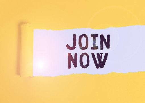Writing note showing Join Now. Business concept for An invite to a demonstrating or a friend to become a member of the group Cardboard which is torn placed above a wooden classic table
