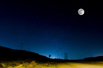 Long exposure shot. Mountain Road through the forest on a full moon night. Scenic night landscape of dark blue sky with moon. Azerbaijan