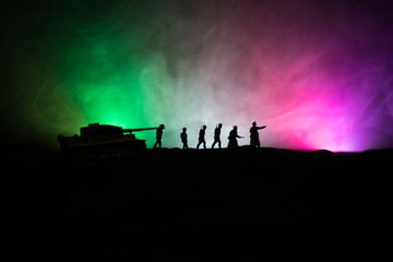 Fototapeta na wymiar War Concept. Military silhouettes fighting scene on war fog sky background, World War German Tanks Silhouettes Below Cloudy Skyline At night. Attack scene. Armored vehicles and infantry.
