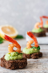 Canapes with avocado mousse and spicy shrimp on brown bread
